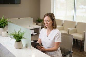 Esthéticienne médicale consultant une tablette numérique à l'accueil d'une clinique esthétique moderne et épurée